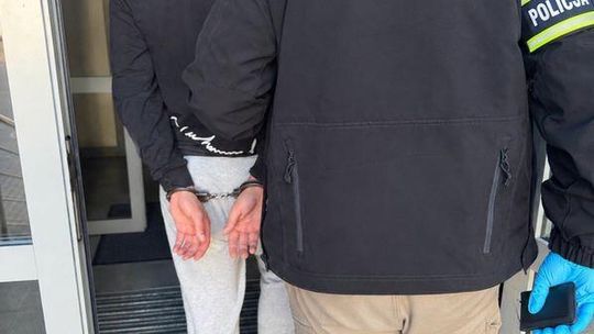 Zatrzymany 21-latek w kajdankach prowadzony przez policjanta