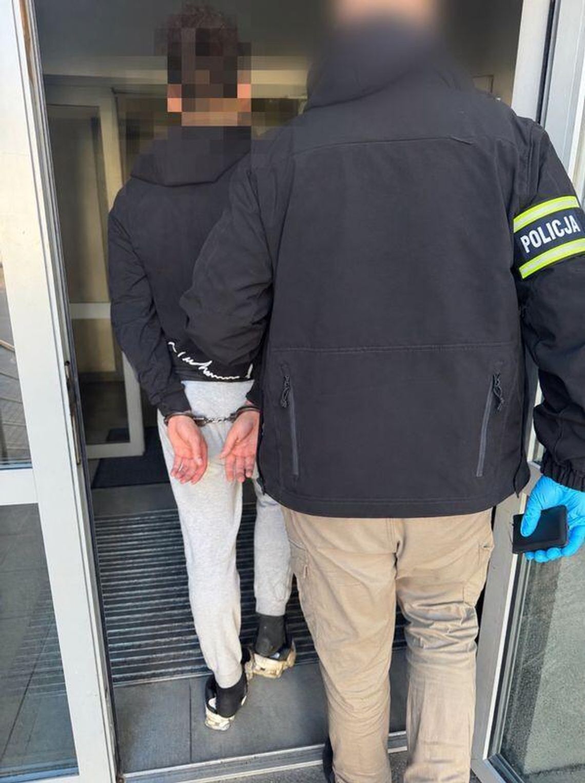 Zatrzymany 21-latek w kajdankach prowadzony przez policjanta