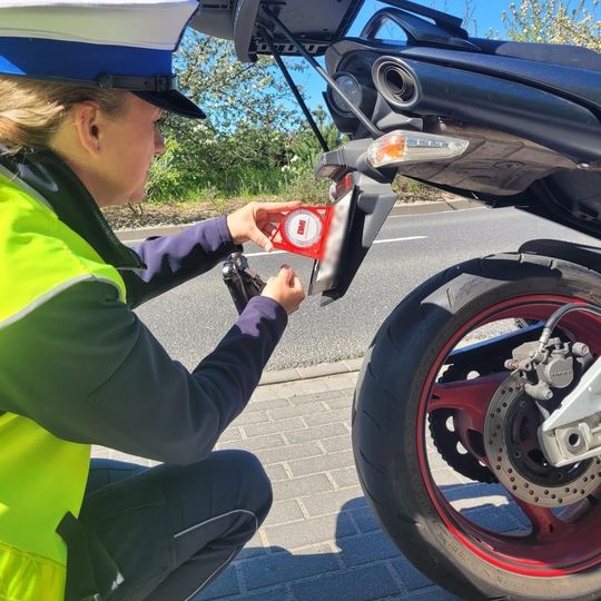 policjanci ze Słupska używają kątomierzy kołowych do pomiaru odgięć tablic rejestracyjnych w motocyklach