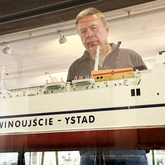 Grzegorz Sudwoj na tle modelu promu M/F „Jan Heweliusz” ze zbiorów Narodowego Muzeum Morskiego w Gdańsku