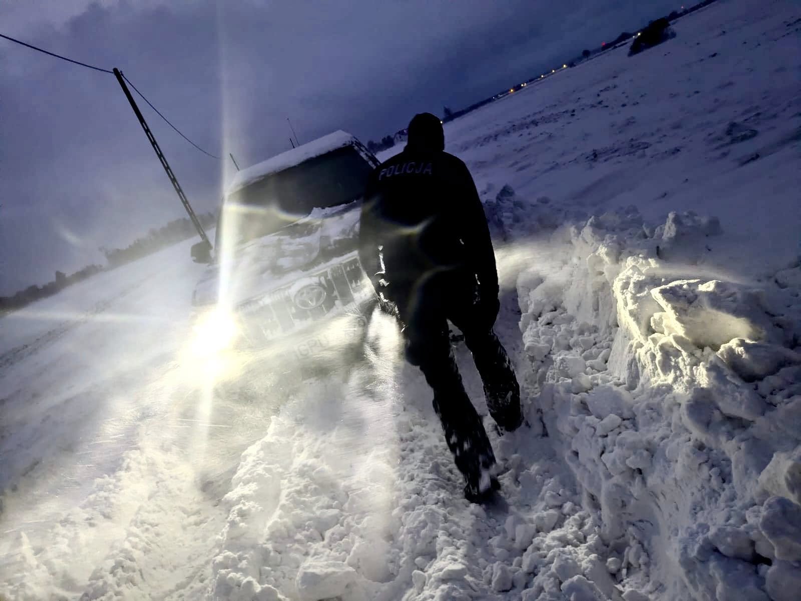 policjant pomagający w odsnieżaniu